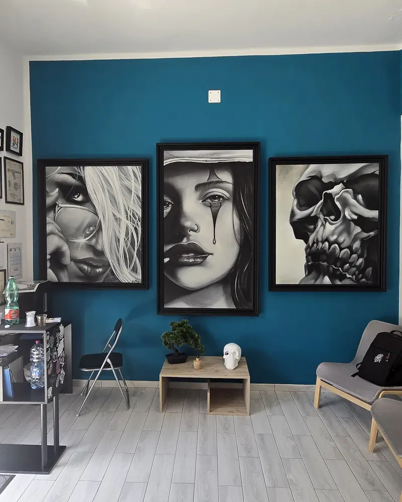 Parete blu dello studio con tre grandi opere in black and grey incorniciate